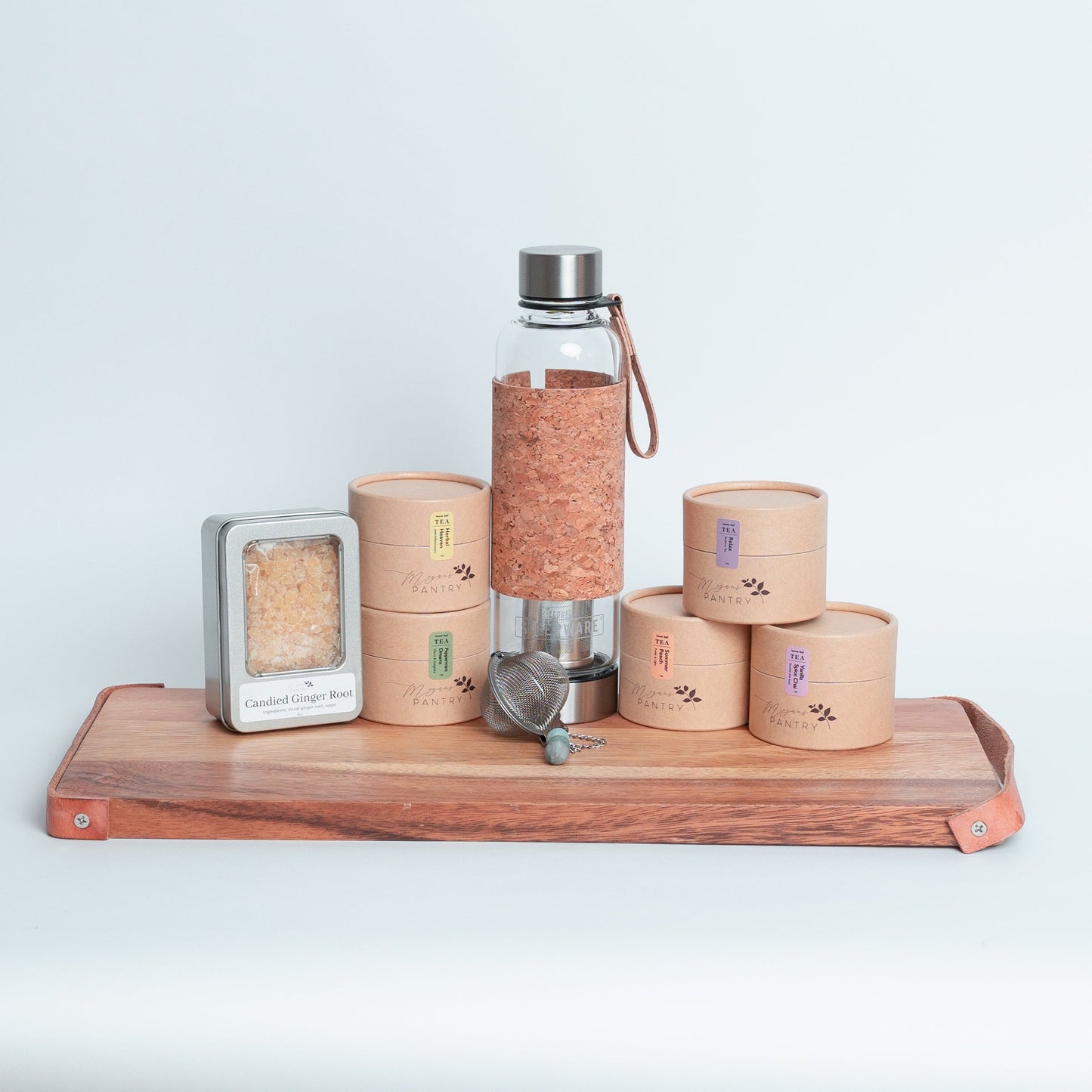 Tea Enthusiast Gift Set from Megan’s Pantry featuring a double-walled glass tea tumbler with built-in infuser, a handmade gemmed stainless steel tea infuser, candied ginger bites, and five loose leaf tea blends. A curated artisan tea gift box perfect for tea lovers, wellness routines, and everyday relaxation.