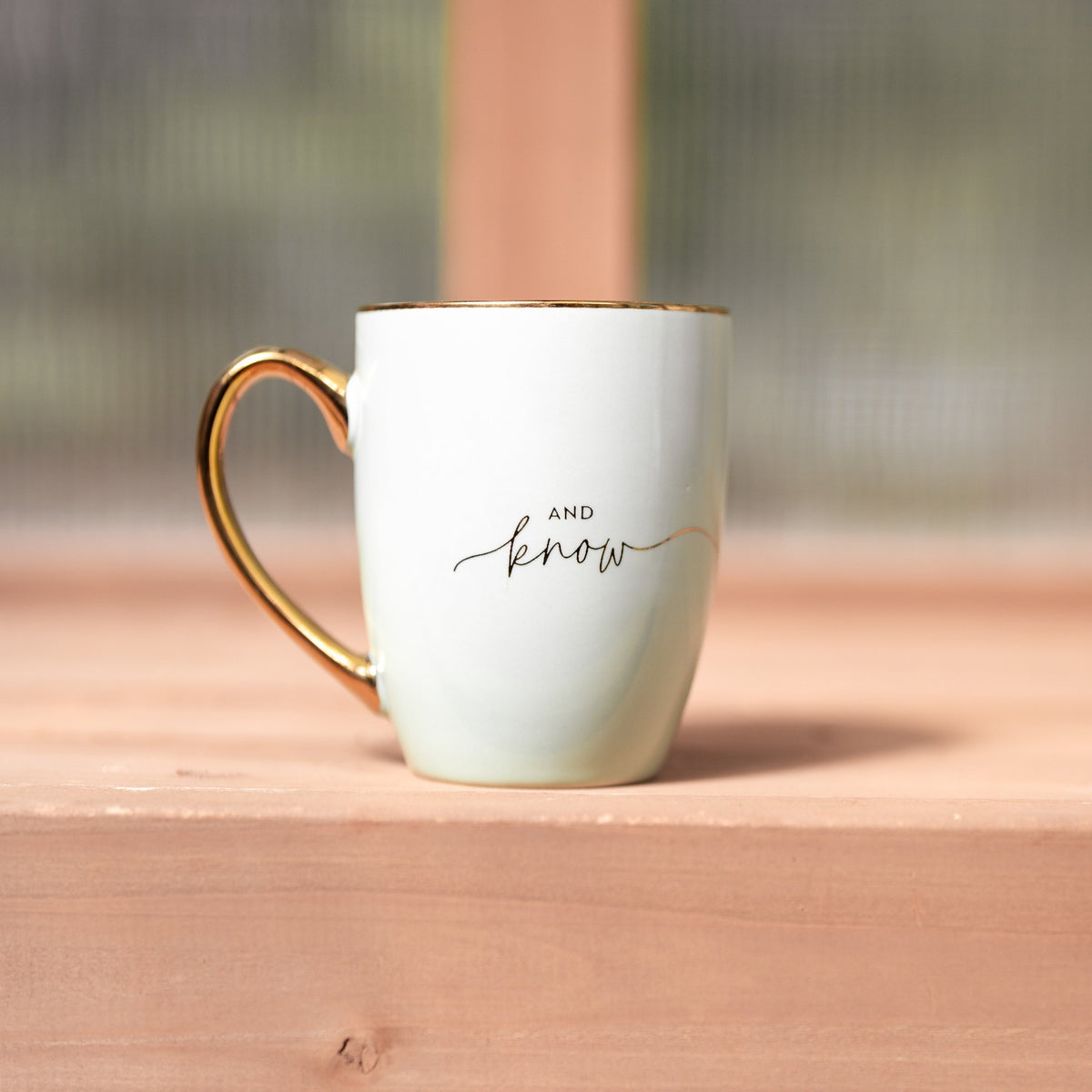 Sage green "be still" ceramic mug from Megan's Pantry, with a cream interior and gold rim and handle.