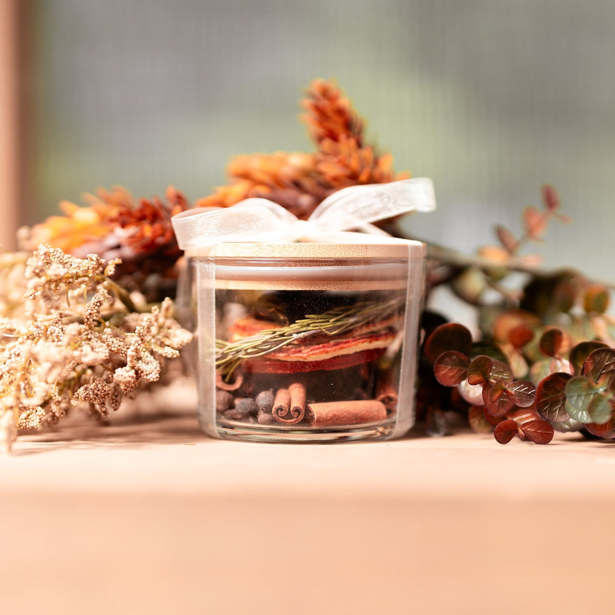 Close-up of dried orange slices, cinnamon sticks, rosemary, whole cloves and allspice berries in a glass jar