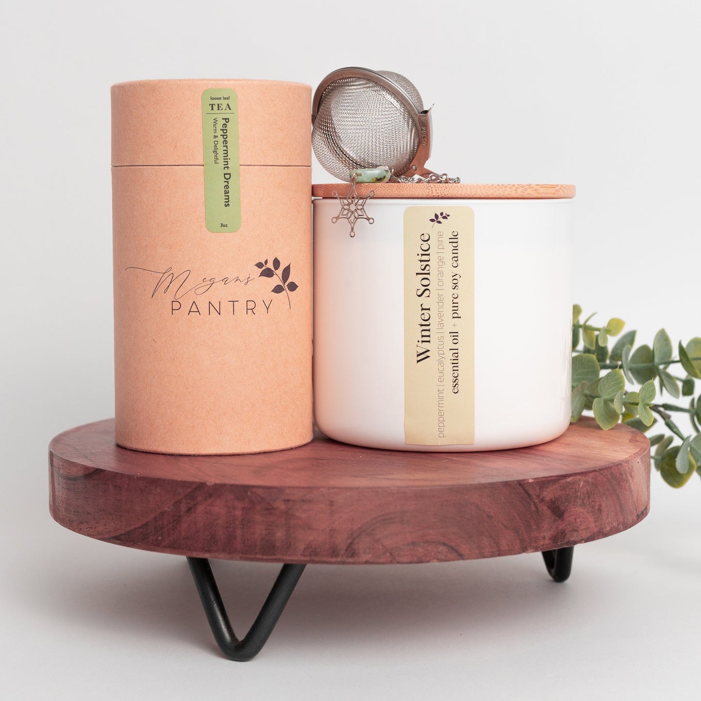 Megan’s Pantry 2025 Holiday Gift Set featuring a winter wellness tea gift box with Peppermint Dreams herbal loose leaf tea (3 oz), a hand-poured soy Winter Solstice Candle (16 oz) with pure essential oils, and a stainless steel snowflake tea ball infuser ornament displayed in a cozy, seasonal setting perfect for Christmas gifting, tea lovers, and holiday self-care.