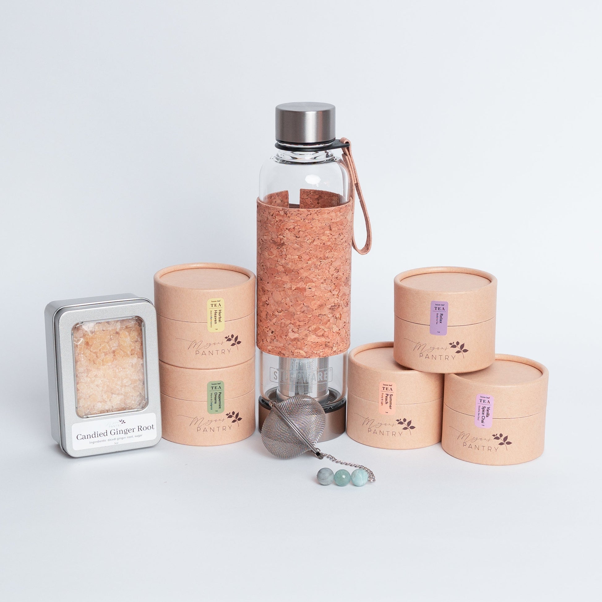 Tea Enthusiast Gift Set from Megan’s Pantry featuring a double-walled glass tea tumbler with built-in infuser, a handmade gemmed stainless steel tea infuser, candied ginger bites, and five loose leaf tea blends. A curated artisan tea gift box perfect for tea lovers, wellness routines, and everyday relaxation.