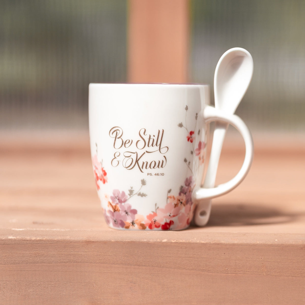 White floral ceramic mug with plum interior and matching spoon from Megan's Pantry, with "Be still & know" in gold foil.
