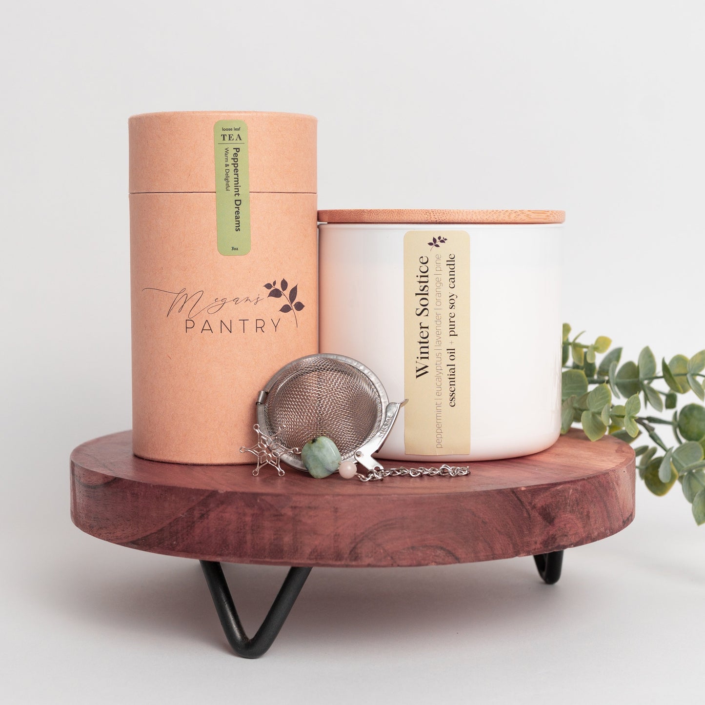Megan’s Pantry 2025 Holiday Gift Set featuring a winter wellness tea gift box with Peppermint Dreams herbal loose leaf tea (3 oz), a hand-poured soy Winter Solstice Candle (16 oz) with pure essential oils, and a stainless steel snowflake tea ball infuser ornament displayed in a cozy, seasonal setting perfect for Christmas gifting, tea lovers, and holiday self-care.