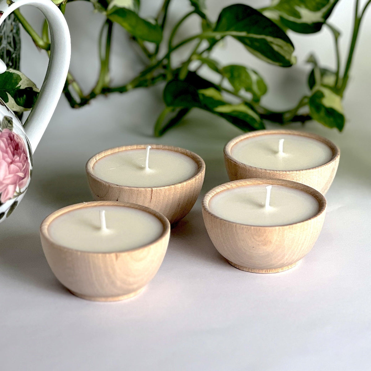 Set of four citronella essential oil soy tealight candles in wooden bowls for outdoor gatherings