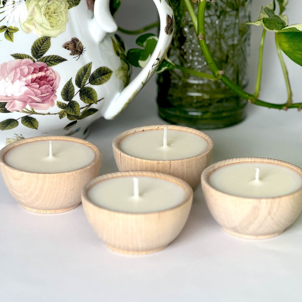 Set of four citronella essential oil soy tealight candles in wooden bowls for outdoor gatherings