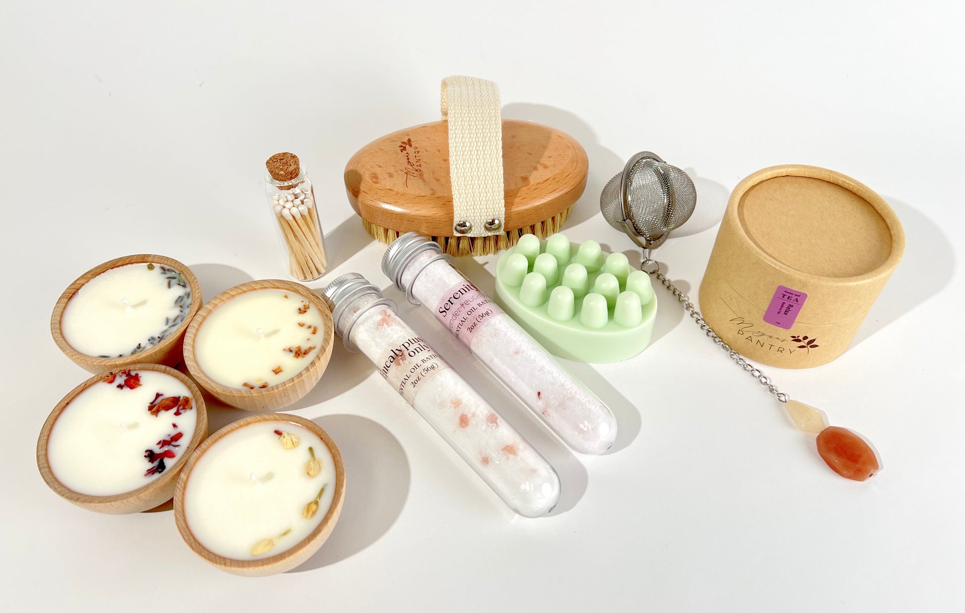 Megan’s Pantry Perfect Spa Day Gift Set featuring a 1 oz pouch of Relax herbal loose leaf tea, a gemmed stainless steel tea infuser, wooden aromatherapy tealight candles (set of 4), a box of matches, Serenity and Eucalyptus bath soaks (2 oz each), Peace triple butter body bar, and a natural bristle body brush — beautifully arranged for a luxurious spa day at home. Ideal wellness gift box for self-care, relaxation, stress relief, and thoughtful gifting.