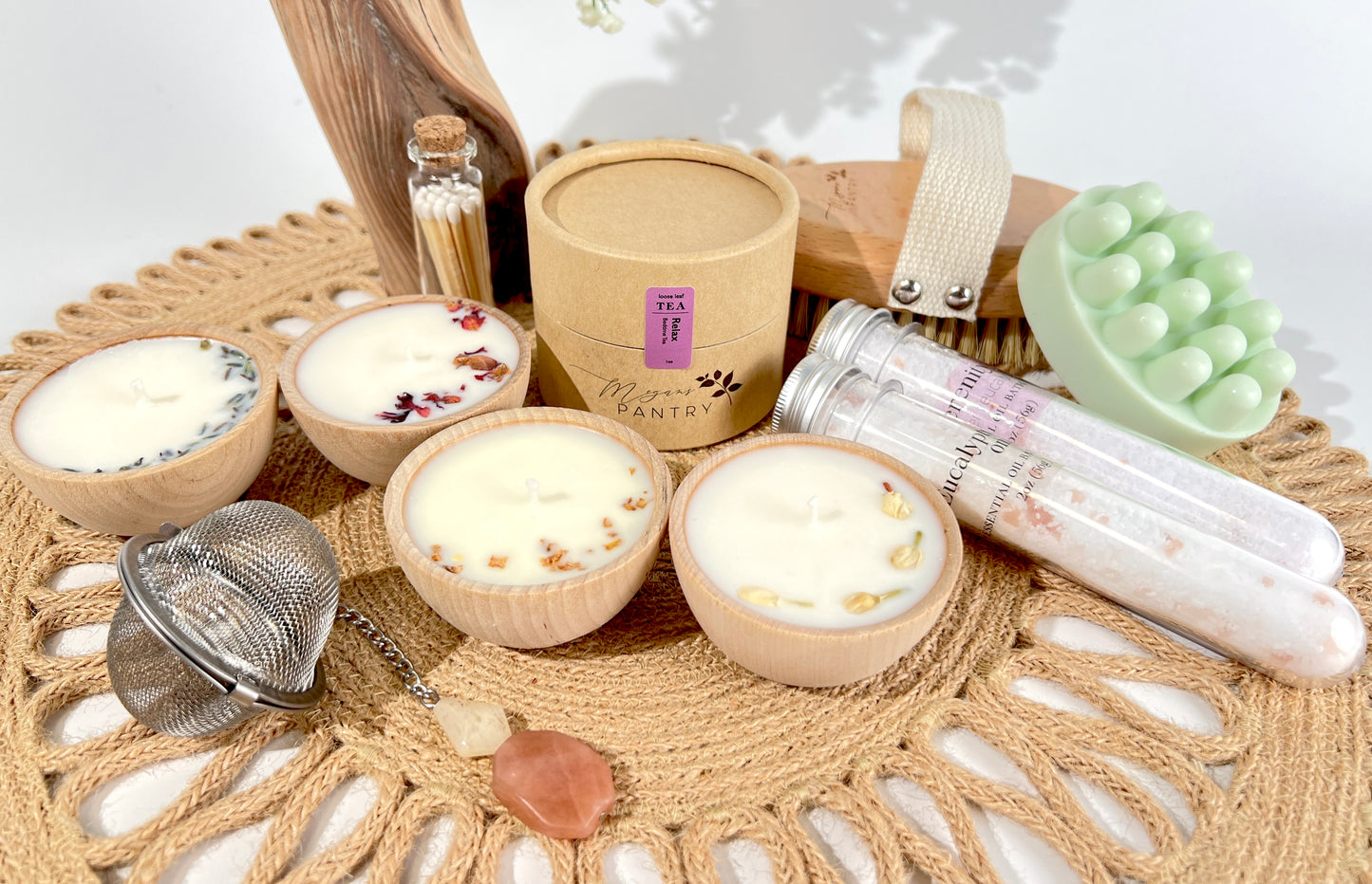 Megan’s Pantry Perfect Spa Day Gift Set featuring a 1 oz pouch of Relax herbal loose leaf tea, a gemmed stainless steel tea infuser, wooden aromatherapy tealight candles (set of 4), a box of matches, Serenity and Eucalyptus bath soaks (2 oz each), Peace triple butter body bar, and a natural bristle body brush — beautifully arranged for a luxurious spa day at home. Ideal wellness gift box for self-care, relaxation, stress relief, and thoughtful gifting.