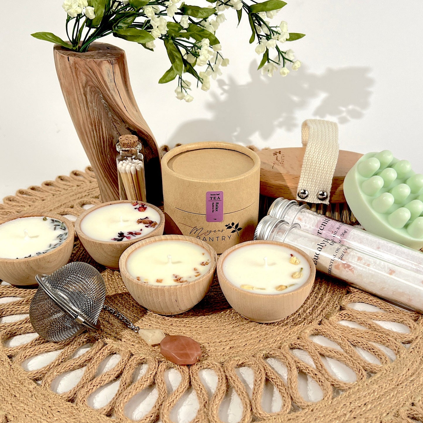 Megan’s Pantry Perfect Spa Day Gift Set featuring a 1 oz pouch of Relax herbal loose leaf tea, a gemmed stainless steel tea infuser, wooden aromatherapy tealight candles (set of 4), a box of matches, Serenity and Eucalyptus bath soaks (2 oz each), Peace triple butter body bar, and a natural bristle body brush — beautifully arranged for a luxurious spa day at home. Ideal wellness gift box for self-care, relaxation, stress relief, and thoughtful gifting.