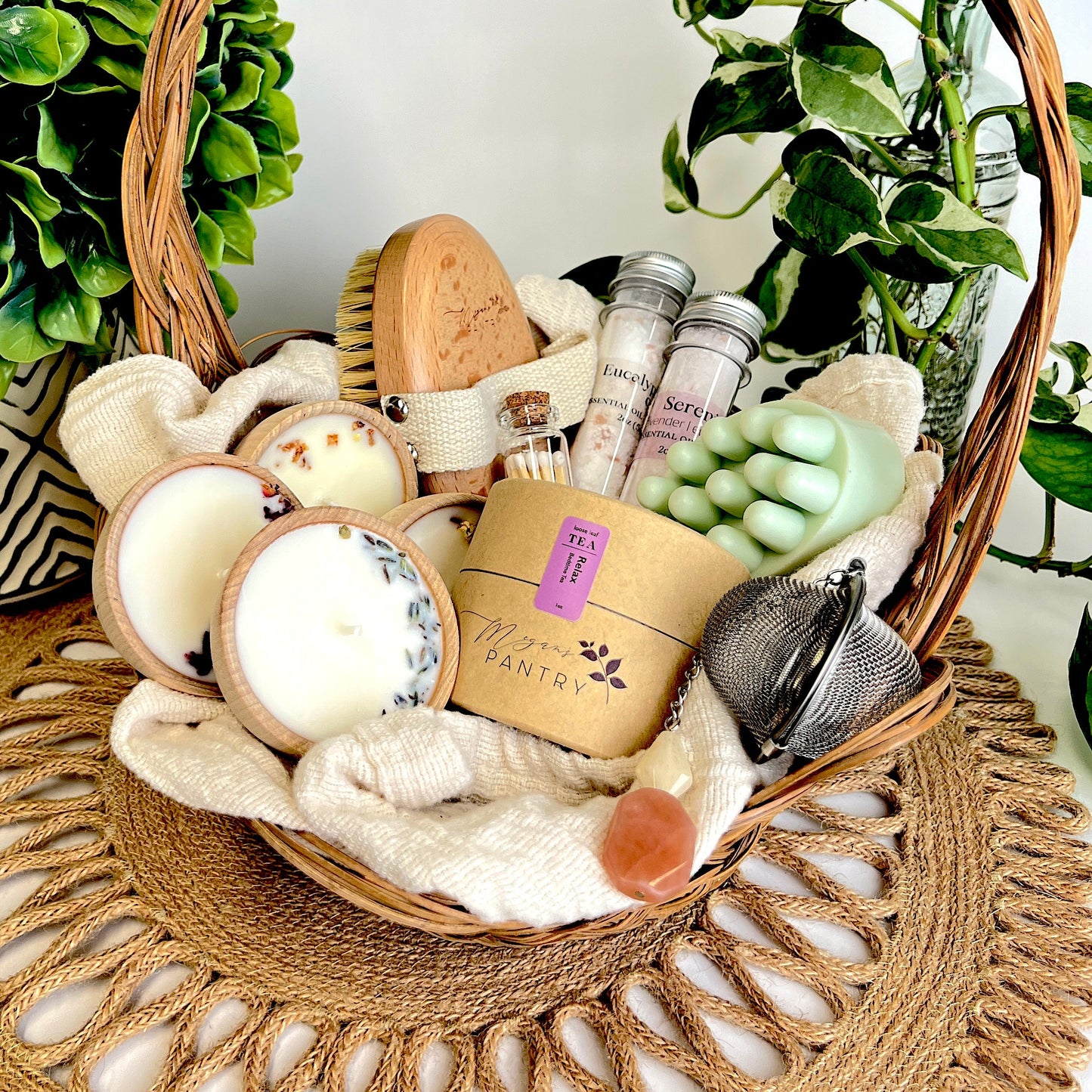 Megan’s Pantry Perfect Spa Day Gift Set featuring a 1 oz pouch of Relax herbal loose leaf tea, a gemmed stainless steel tea infuser, wooden aromatherapy tealight candles (set of 4), a box of matches, Serenity and Eucalyptus bath soaks (2 oz each), Peace triple butter body bar, and a natural bristle body brush — beautifully arranged for a luxurious spa day at home. Ideal wellness gift box for self-care, relaxation, stress relief, and thoughtful gifting.