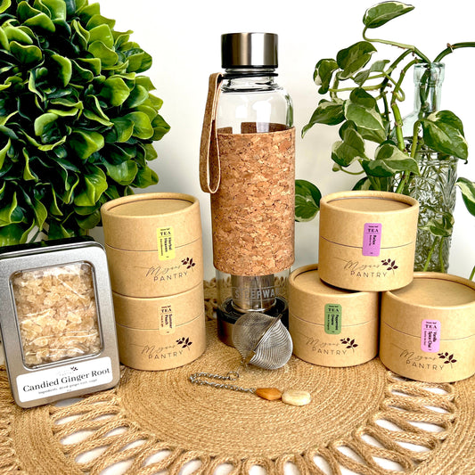Megan’s Pantry Tea Enthusiast Gift Set featuring a premium glass Urban Tea Tumbler with built-in infuser, a gemmed stainless steel tea ball infuser (styles vary), a 5 oz bag of sulfite-free candied ginger bites, and five 1 oz pouches of artisan loose leaf tea blends — including Vanilla Spice Chai, Herbal Heaven, Peppermint Dreams, Summer Peach, and Relax Tea. A perfect tea lover’s sampler gift box for birthdays, holidays, wellness routines, or on-the-go tea enjoyment.