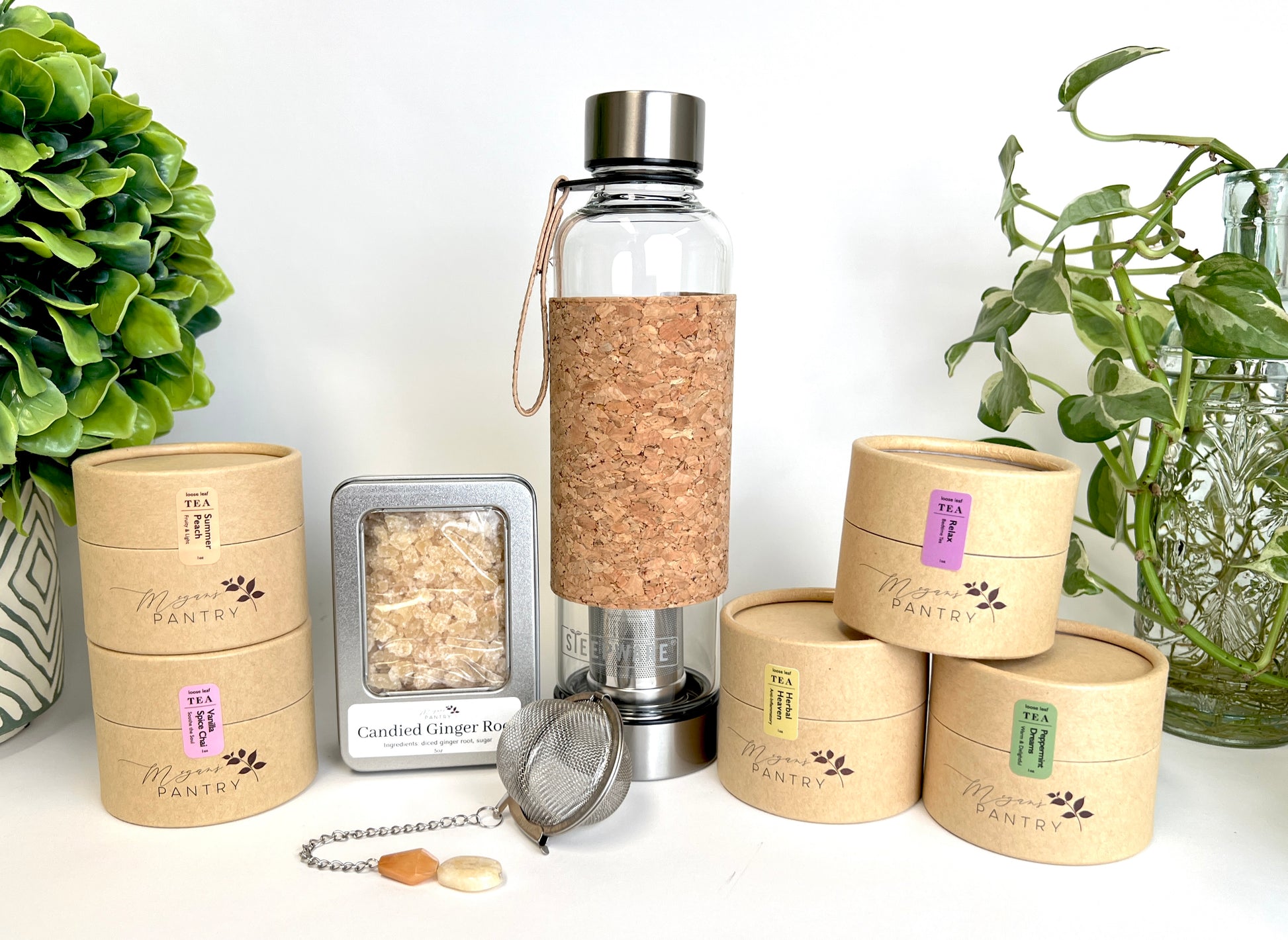 Megan’s Pantry Tea Enthusiast Gift Set featuring a premium glass Urban Tea Tumbler with built-in infuser, a gemmed stainless steel tea ball infuser (styles vary), a 5 oz bag of sulfite-free candied ginger bites, and five 1 oz pouches of artisan loose leaf tea blends — including Vanilla Spice Chai, Herbal Heaven, Peppermint Dreams, Summer Peach, and Relax Tea. A perfect tea lover’s sampler gift box for birthdays, holidays, wellness routines, or on-the-go tea enjoyment.