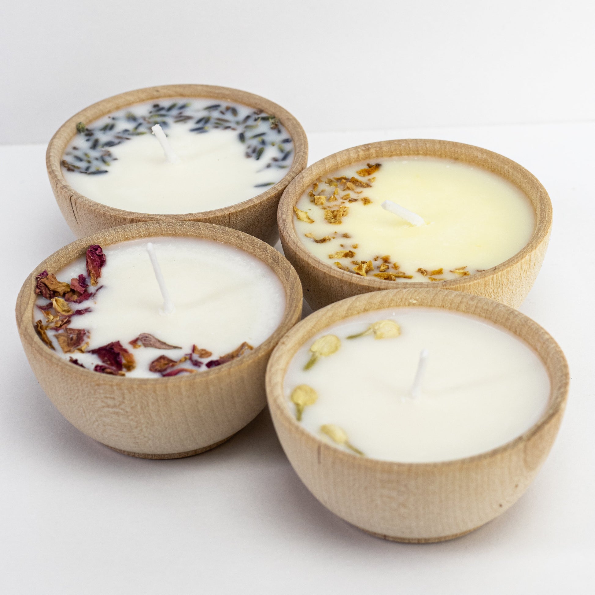Set of four essential oil soy tealight candles from Megan’s Pantry in reusable wooden bowls, adorned with botanicals—natural, eco-friendly aromatherapy gift set.