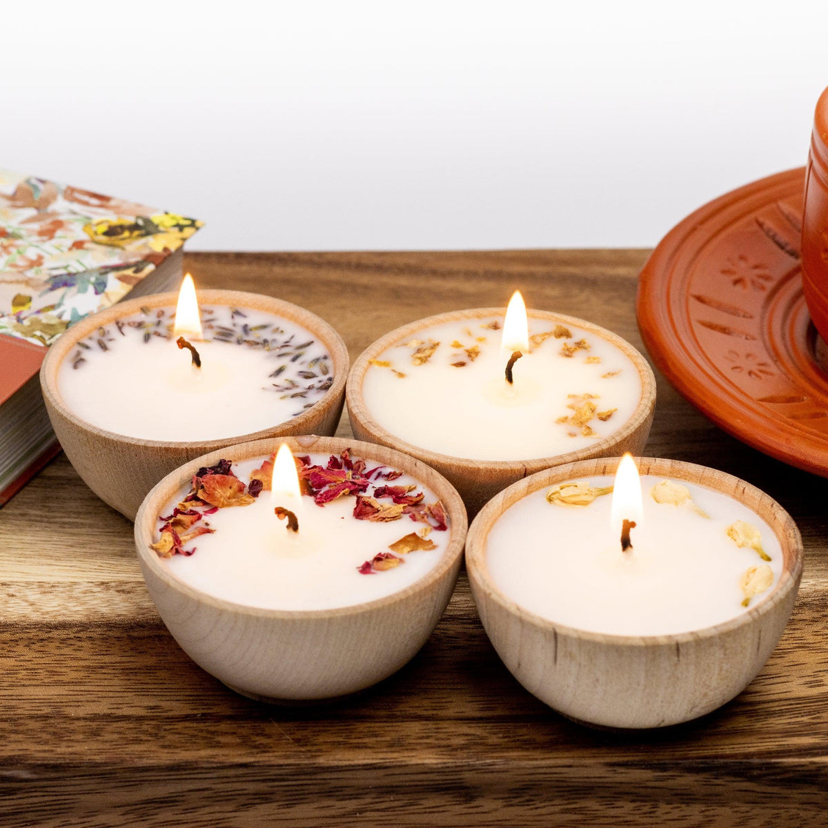 Set of four essential oil soy tealight candles from Megan’s Pantry in reusable wooden bowls, adorned with botanicals—natural, eco-friendly aromatherapy gift set.