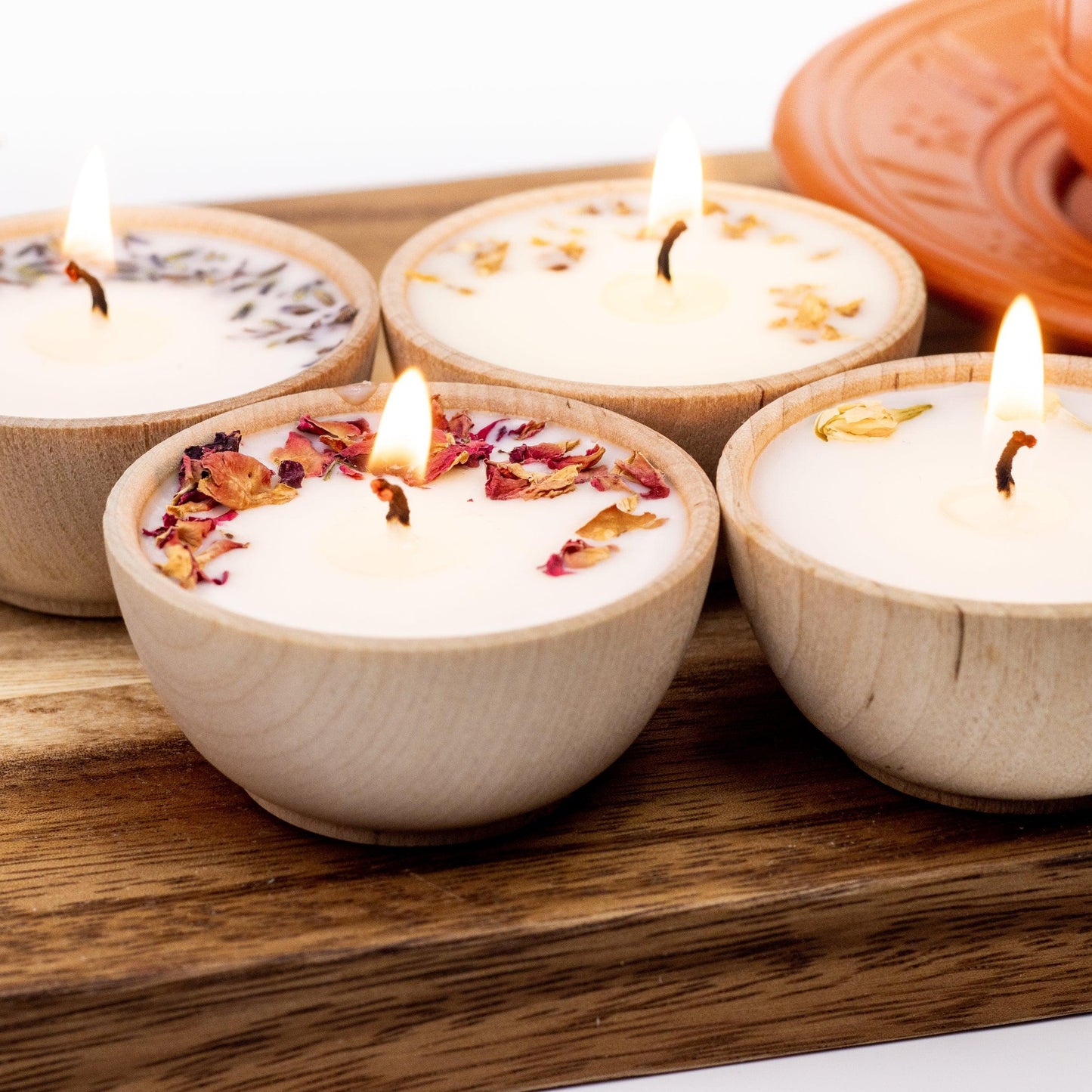 Set of four essential oil soy tealight candles from Megan’s Pantry in reusable wooden bowls, adorned with botanicals—natural, eco-friendly aromatherapy gift set.