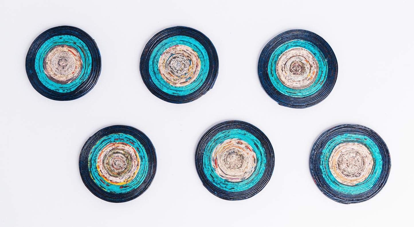 Megan’s Pantry Recycled Newspaper Coaster Set featuring six hand-crafted round coasters made from colorful upcycled newspaper, with a matching holder. Each eco-friendly coaster measures 4 inches in diameter and fits into a 4.5-inch holder. A sustainable and unique home décor gift, perfect for housewarmings, eco-conscious gifting, and colorful coffee table accessories