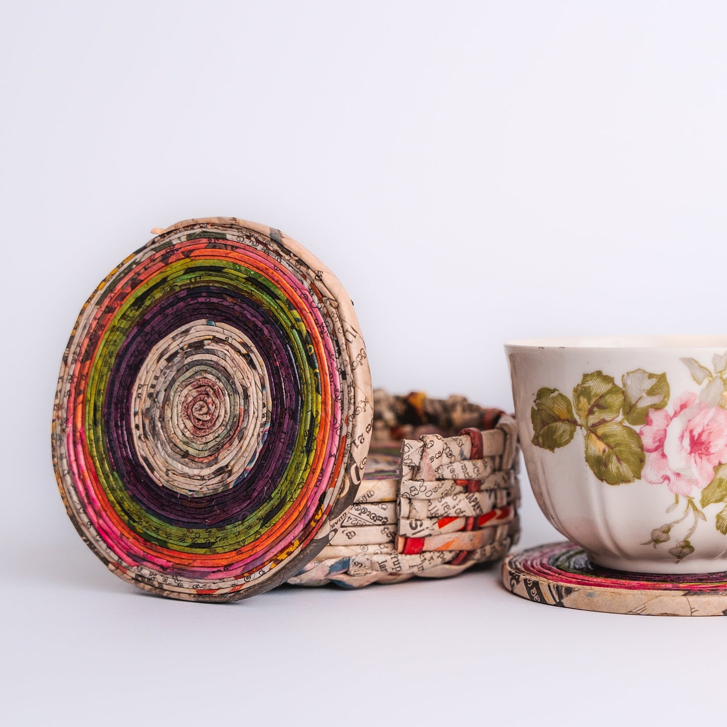 Megan’s Pantry Recycled Newspaper Coaster Set featuring six hand-crafted round coasters made from colorful upcycled newspaper, with a matching holder. Each eco-friendly coaster measures 4 inches in diameter and fits into a 4.5-inch holder. A sustainable and unique home décor gift, perfect for housewarmings, eco-conscious gifting, and colorful coffee table accessories