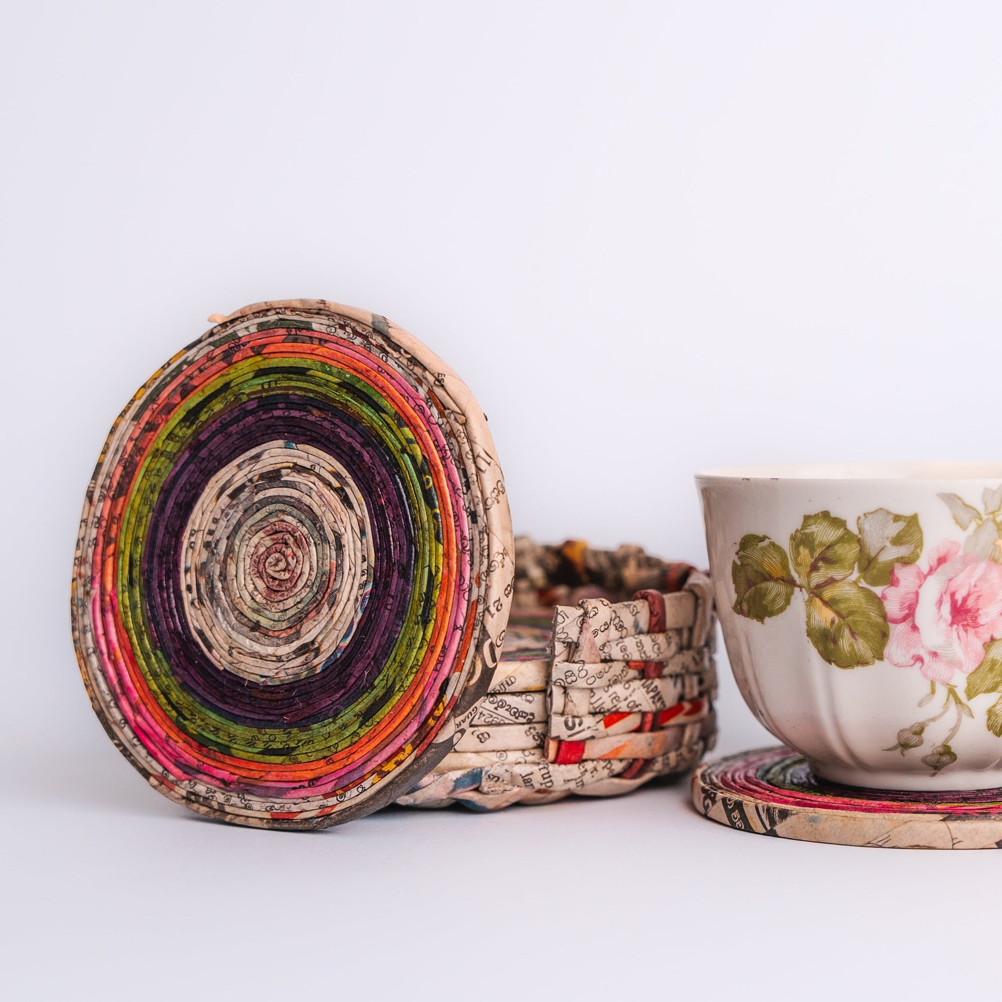 Megan’s Pantry Recycled Newspaper Coaster Set featuring six hand-crafted round coasters made from colorful upcycled newspaper, with a matching holder. Each eco-friendly coaster measures 4 inches in diameter and fits into a 4.5-inch holder. A sustainable and unique home décor gift, perfect for housewarmings, eco-conscious gifting, and colorful coffee table accessories